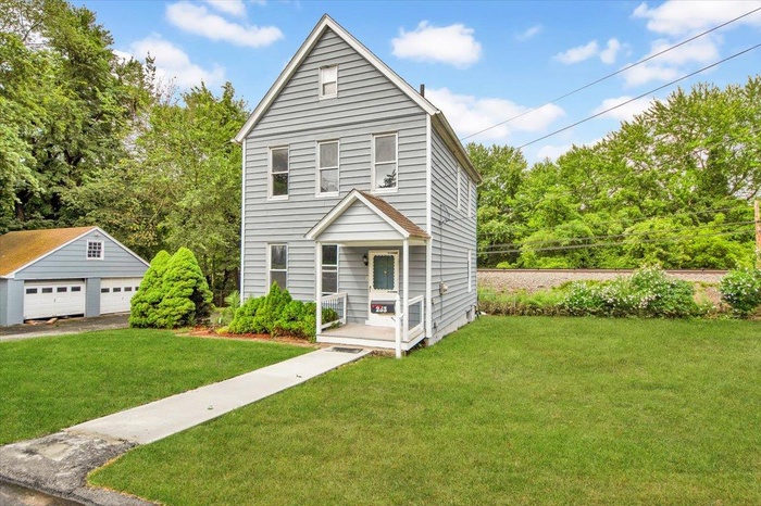 Traditional-style home featuring an outdoor structure, a front lawn, and a garage