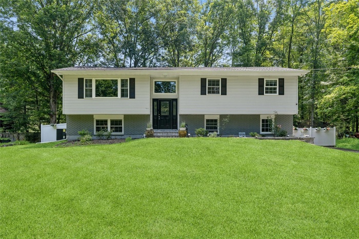 Raised ranch with a front lawn, brick siding, and entry steps