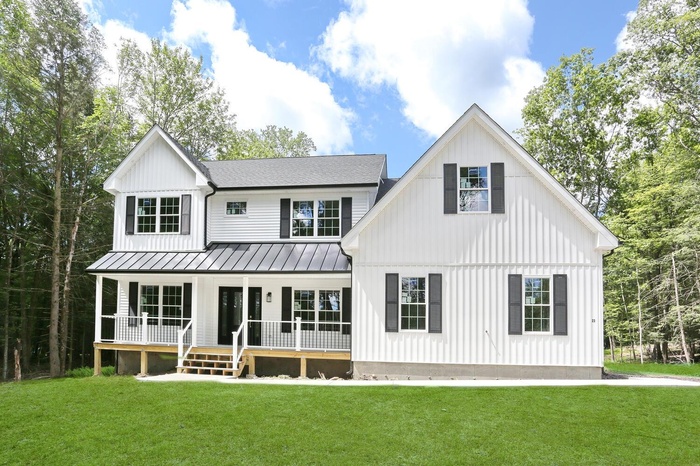 Rear view of property featuring a porch, a standing seam roof, a lawn, and board and batten siding