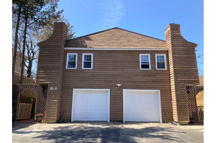 View of property exterior featuring aphalt driveway, a garage, and a chimney