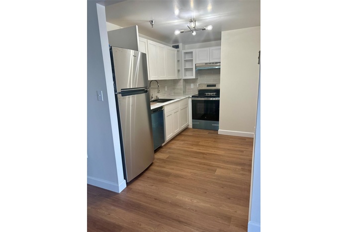 Kitchen featuring stainless steel appliances, under cabinet range hood, white cabinetry, open shelves, and backsplash