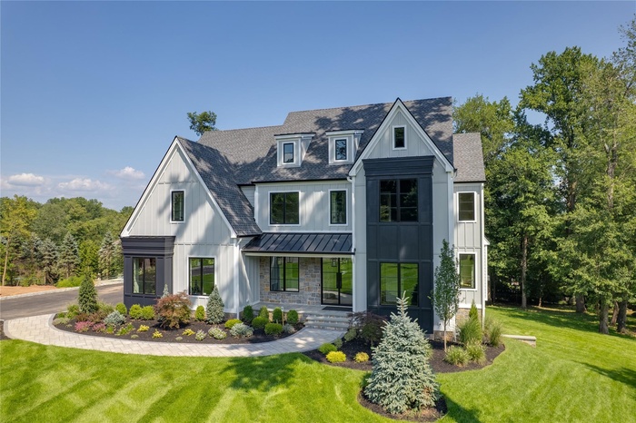 Modern inspired farmhouse with a porch, a front lawn, a standing seam roof, board and batten siding, and roof with shingles