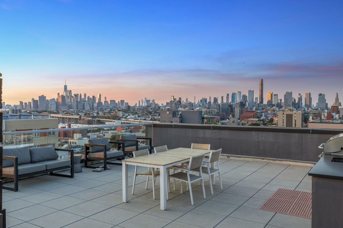 Patio terrace at dusk featuring outdoor lounge area and a view of skyline