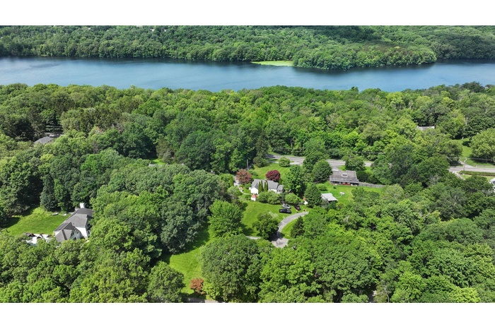 Aerial view of property's location featuring a heavily wooded area and a large body of water