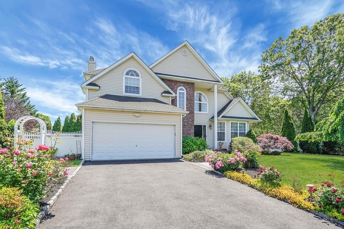 Traditional home with a chimney, driveway, and an attached garage