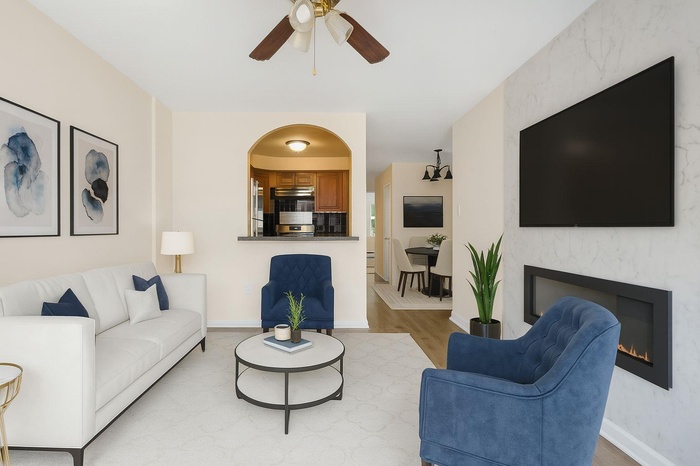 Living area featuring ceiling fan, wood finished floors, arched walkways, and a premium fireplace