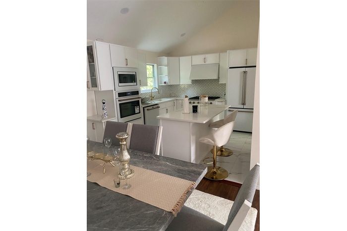 Kitchen with white cabinets, wall oven, refrigerator, tasteful backsplash, and lofted ceiling