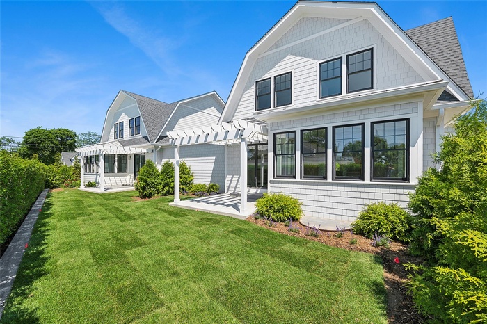 Back of property with a pergola, a shingled roof, a patio area, and a yard