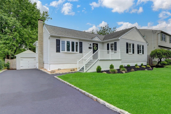 Ranch-style house featuring a garage, a front lawn, and large driveway