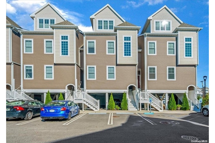 View of property with stairs and uncovered parking