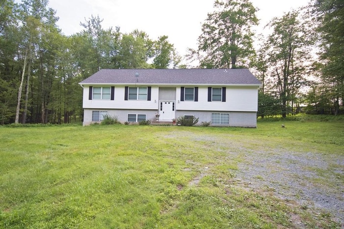 Raised ranch featuring a front lawn and entry steps