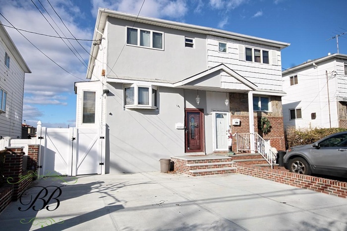 View of front of house featuring stucco siding, a gate, and brick siding