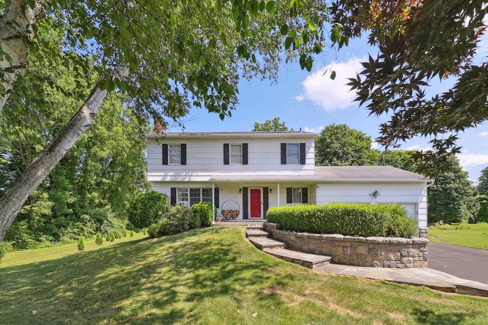 Traditional-style home with a garage, a front yard, and driveway