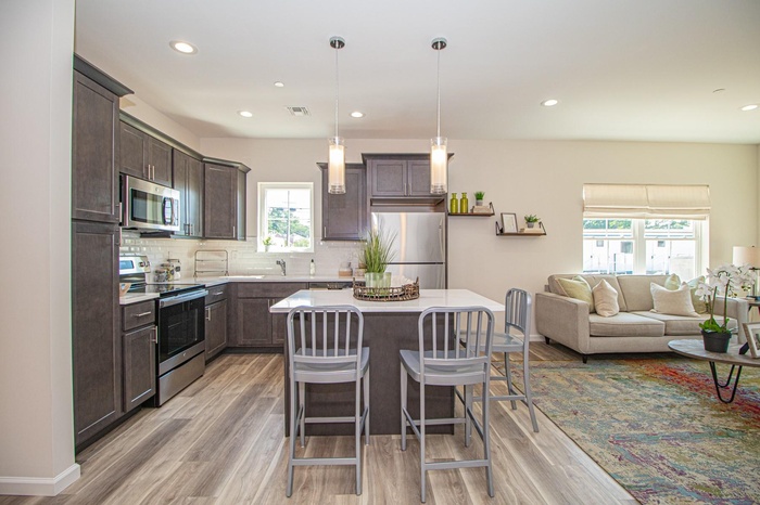 Kitchen with stainless steel appliances, visible vents, a kitchen breakfast bar, dark brown cabinets, and tasteful backsplash