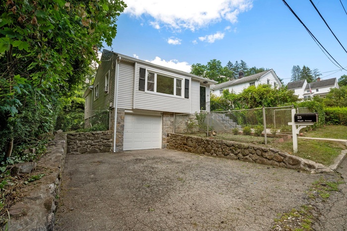 View of front facade with stone siding, a garage, asphalt driveway, and stairway