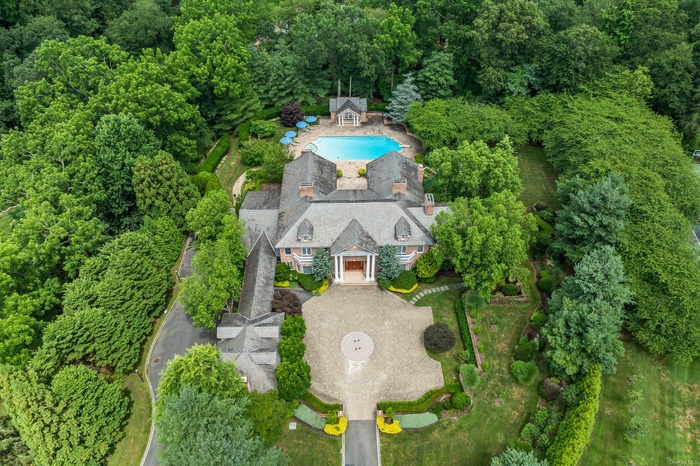 Aerial view of property and surrounding area featuring a forest and a pool area