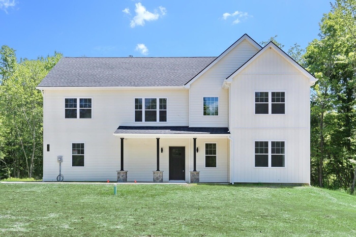 Modern inspired farmhouse with a front yard, a porch, and roof with shingles