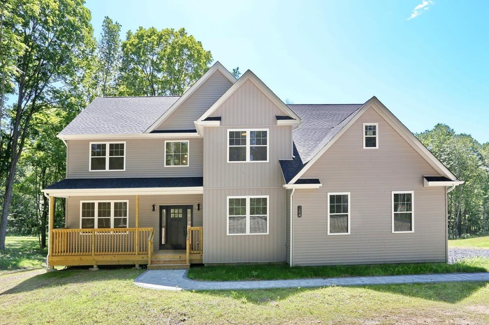 View of front of home featuring roof with shingles, a front lawn, and a porch