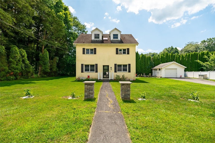 View of front of home featuring a detached garage, stucco siding, and an outdoor structure