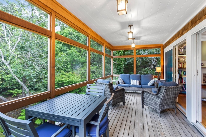 Sunroom / solarium featuring healthy amount of natural light, an outdoor hangout area, and view of wooded area