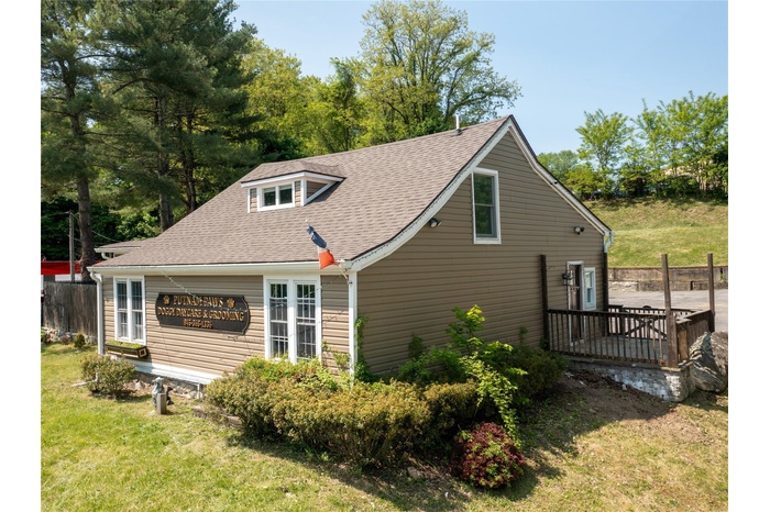 View of side of property featuring roof with shingles, a yard, and a deck