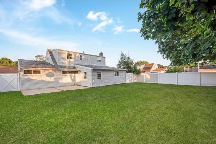 Rear view of property featuring a fenced backyard, a chimney, a patio area, and a gate