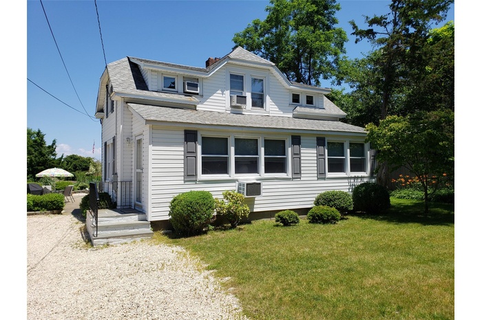 View of front of house with a shingled roof, a front yard, and a chimney