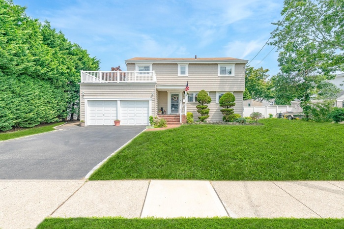 View of front of house with a balcony, asphalt driveway, and a garage