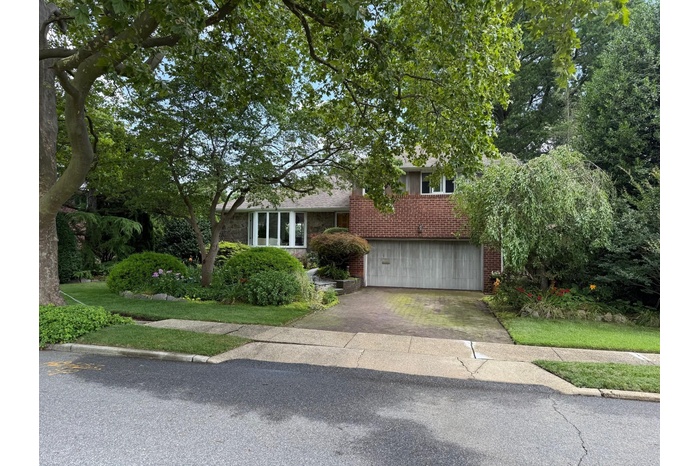 Split level home with brick siding, an attached garage, and concrete driveway