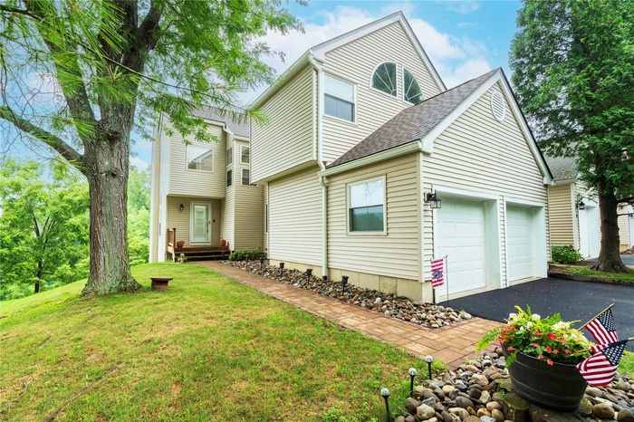 View of front of property with asphalt driveway, a garage, a shingled roof, and a front yard