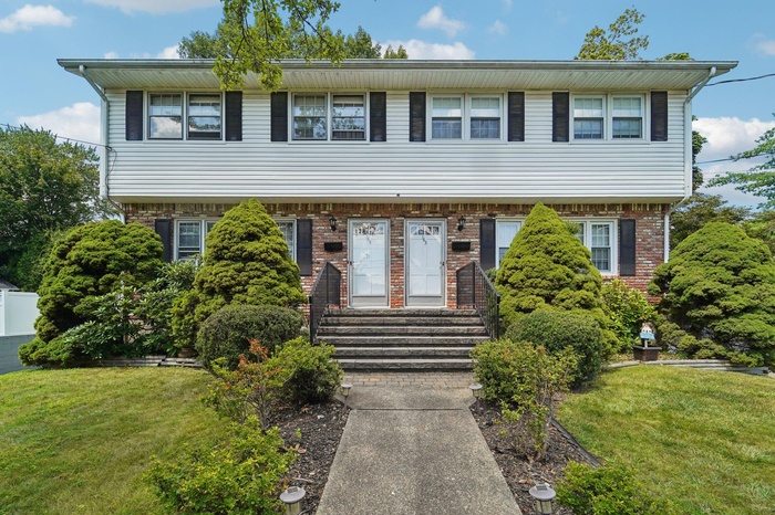 Colonial home featuring a front yard and brick siding