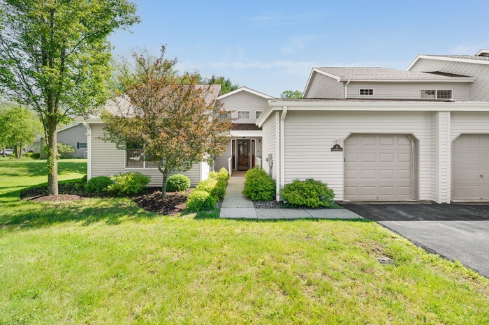 View of front of house with asphalt driveway, a front lawn, and a garage