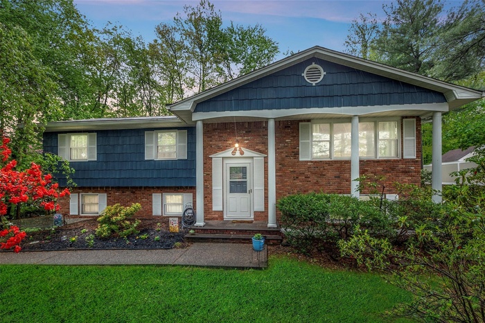 Raised ranch featuring brick siding and a front lawn