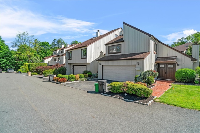 View of property with an attached garage and asphalt driveway