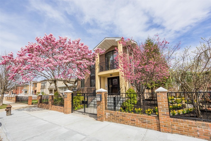 View of front facade with a balcony, a fenced front yard, and a gate