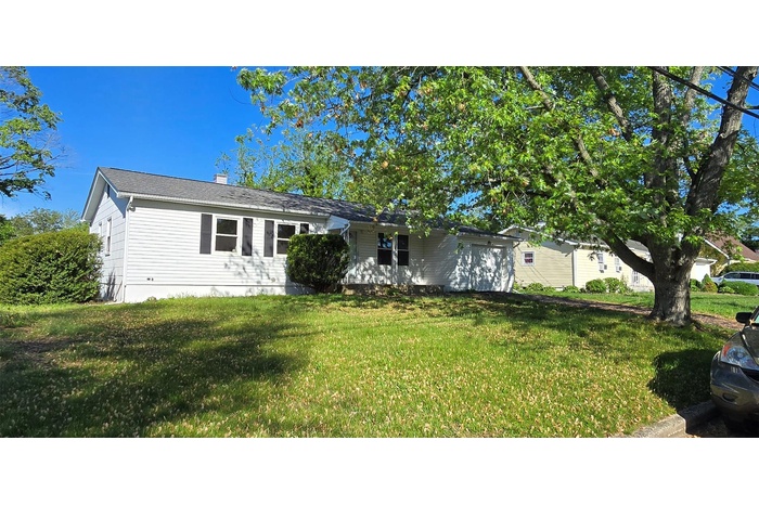 View of front of property with a garage, a chimney, and a front lawn