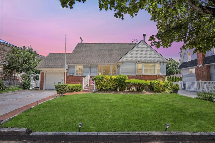 View of front of house with an attached garage, brick siding, driveway, and a shingled roof