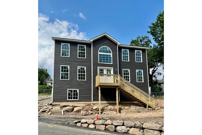 View of front of property featuring stairway and a wooden deck