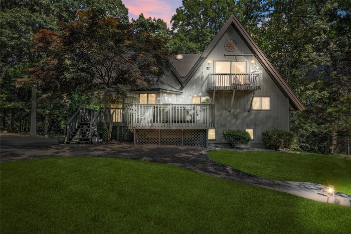 Back of property featuring a yard, a balcony, and a wooden deck