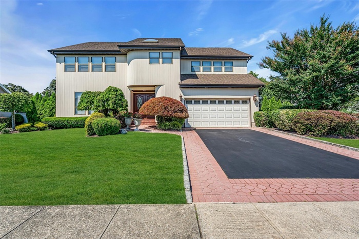 View of front facade featuring asphalt driveway, a garage, a shingled roof, and a front lawn