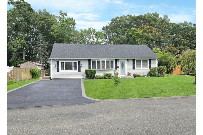 Ranch-style house with roof with shingles, driveway, and view of scattered trees