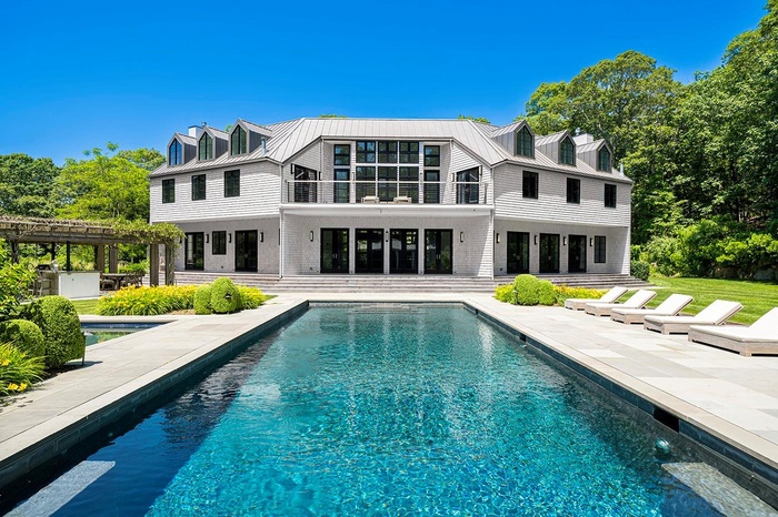Rear view of property with a balcony, a patio, a metal roof, and an outdoor pool