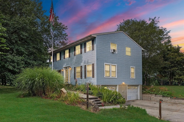 Colonial home with an attached garage, driveway, and a front lawn