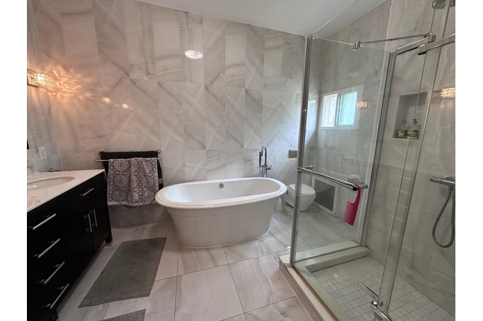 Bathroom with tile walls, vanity, a soaking tub, a shower stall, and tile patterned floors