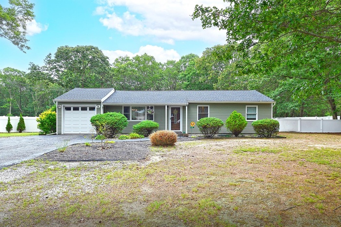 Ranch-style home with an attached garage, driveway, and a shingled roof