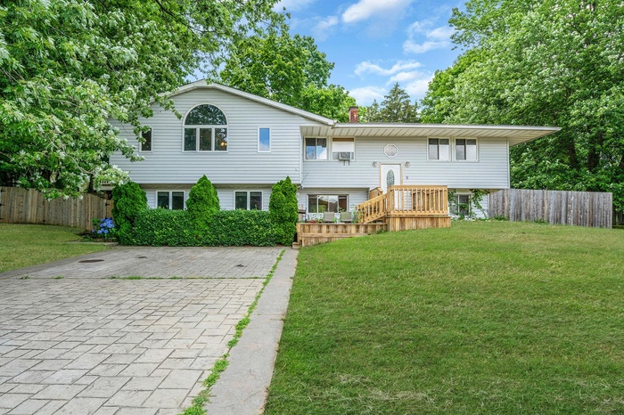 Back of house featuring decorative driveway and a chimney