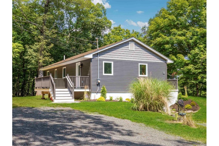 View of front of house with a front lawn and view of wooded area