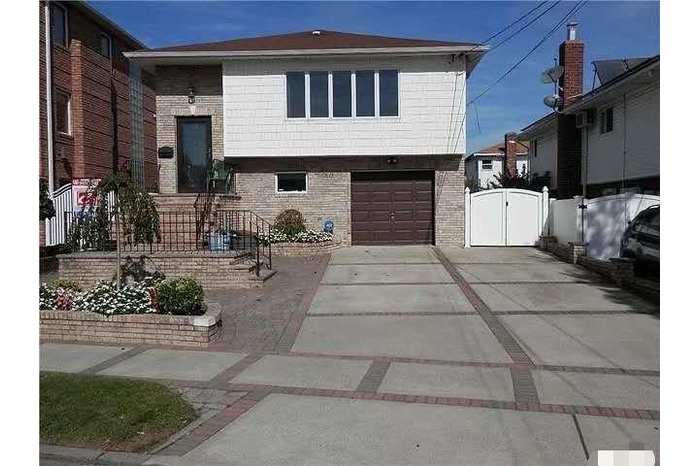 View of front of home featuring brick siding, a gate, concrete driveway, and a garage