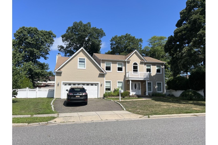 Colonial home with driveway, a balcony, a garage, and a chimney