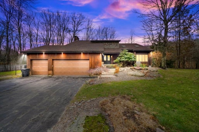 View of front of house featuring driveway, a garage, and a chimney